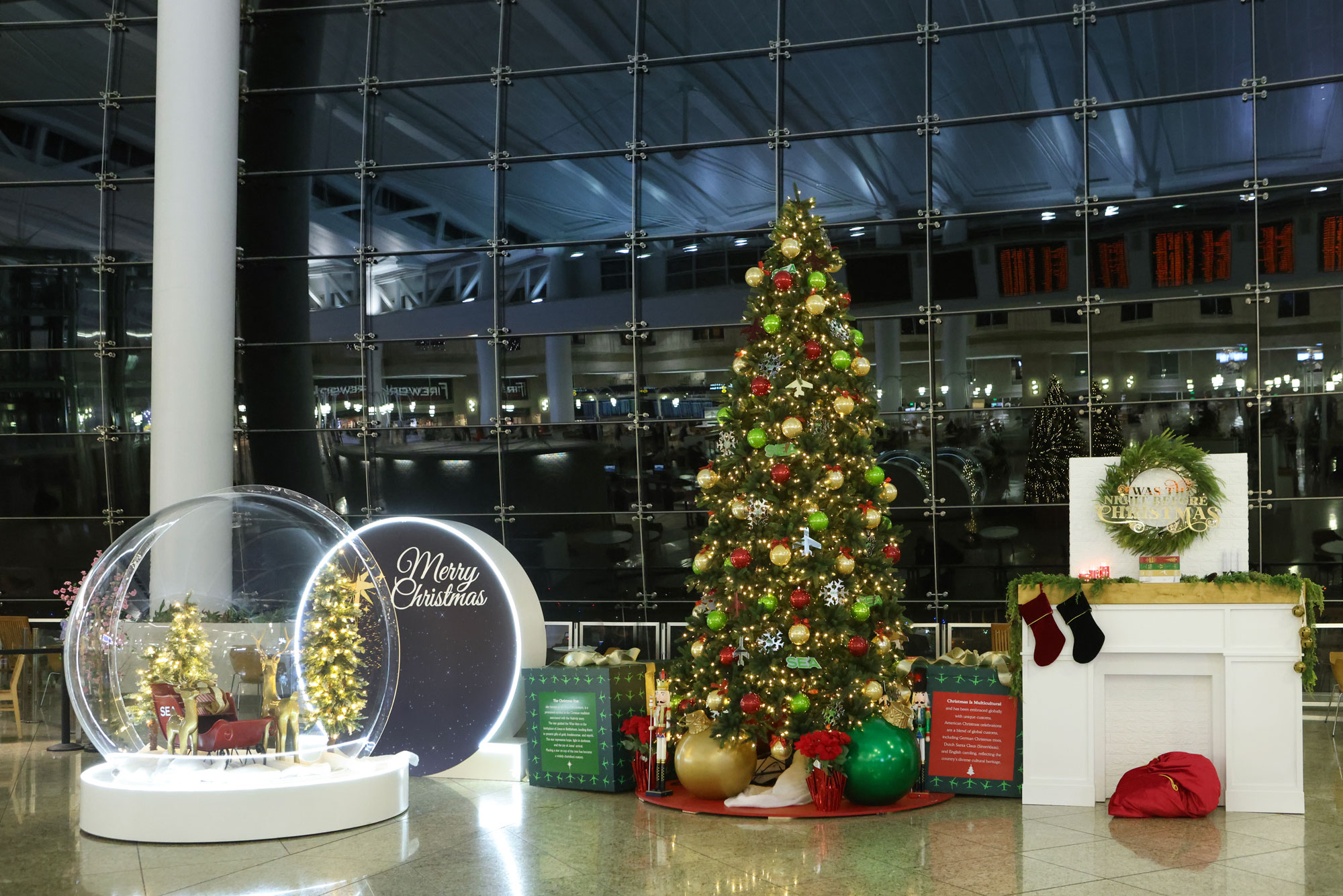 SEA Airport holiday decor in central terminal - includes Christmas tree, gifts, fireplace and globe with reindeer and sleigh