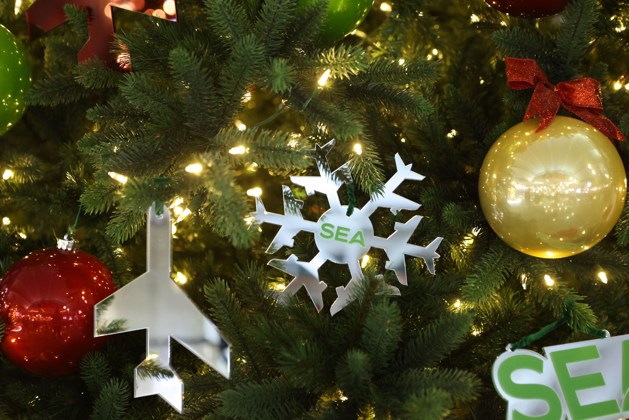 SEA Airport's Holiday Ornaments including SEA snowflake, airplane and gold/yellow ornaments