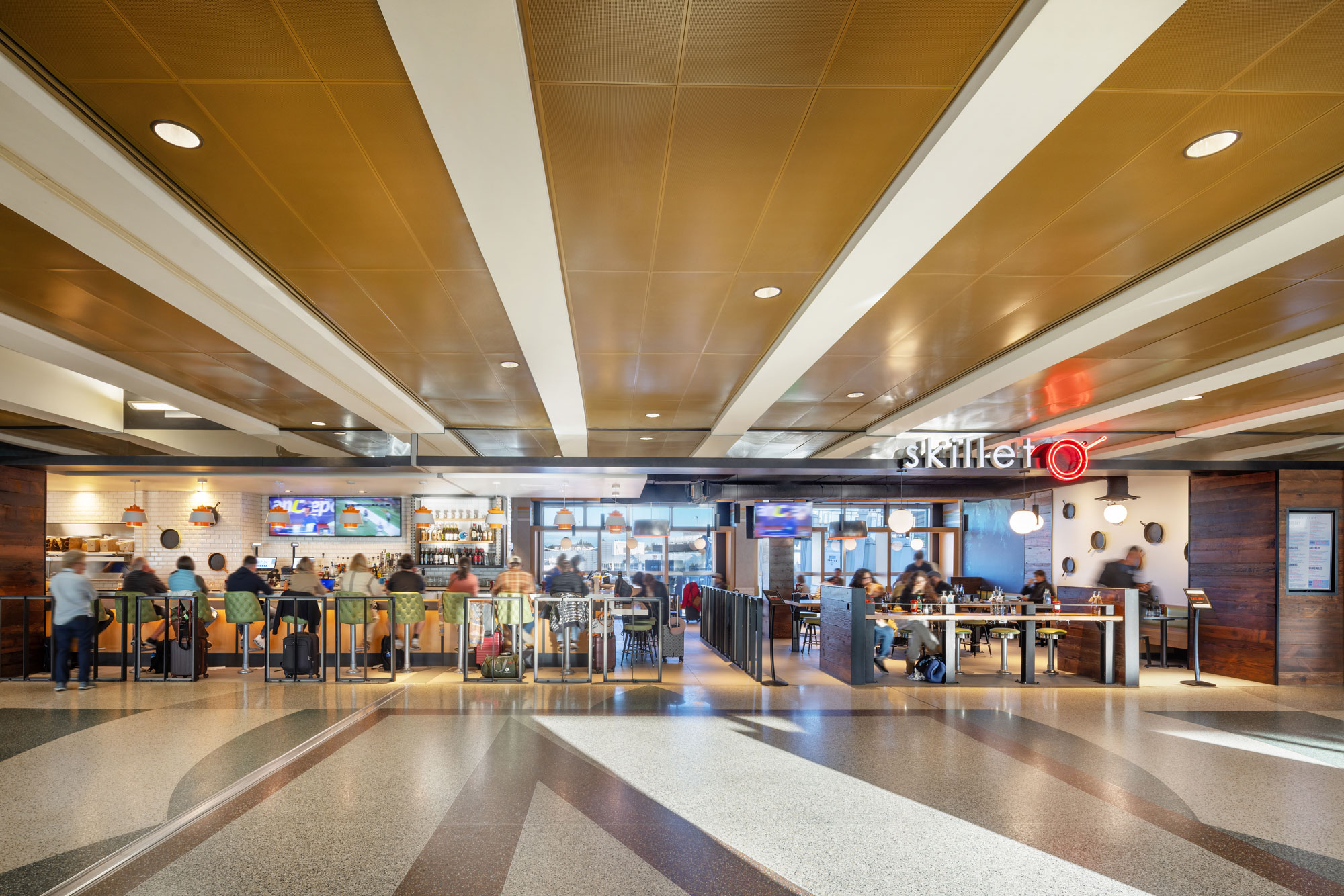 Skillet (C Concourse) exterior with travelers at the bar and sit-down area