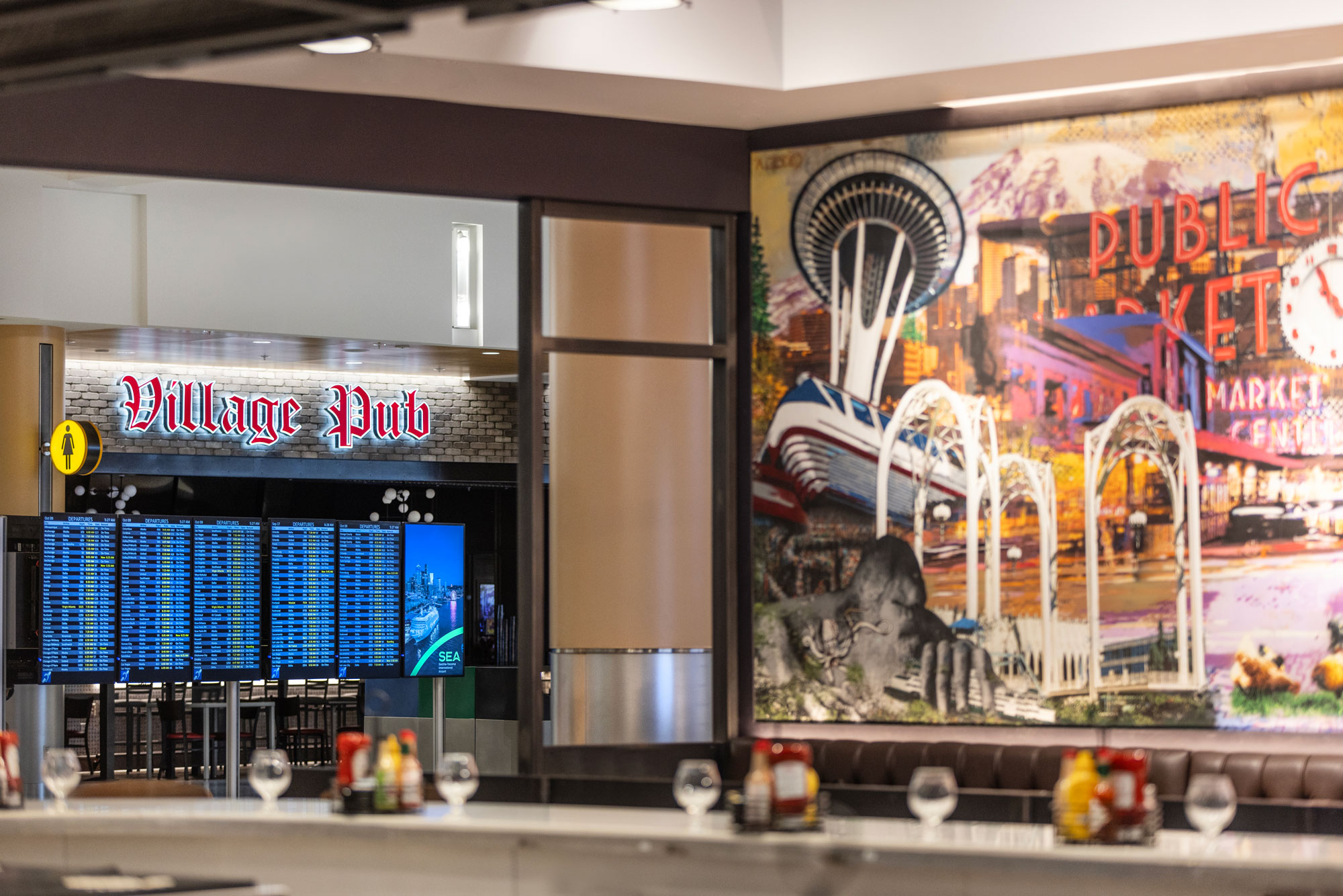 Village Pub interior artwork with flight information displays in the background