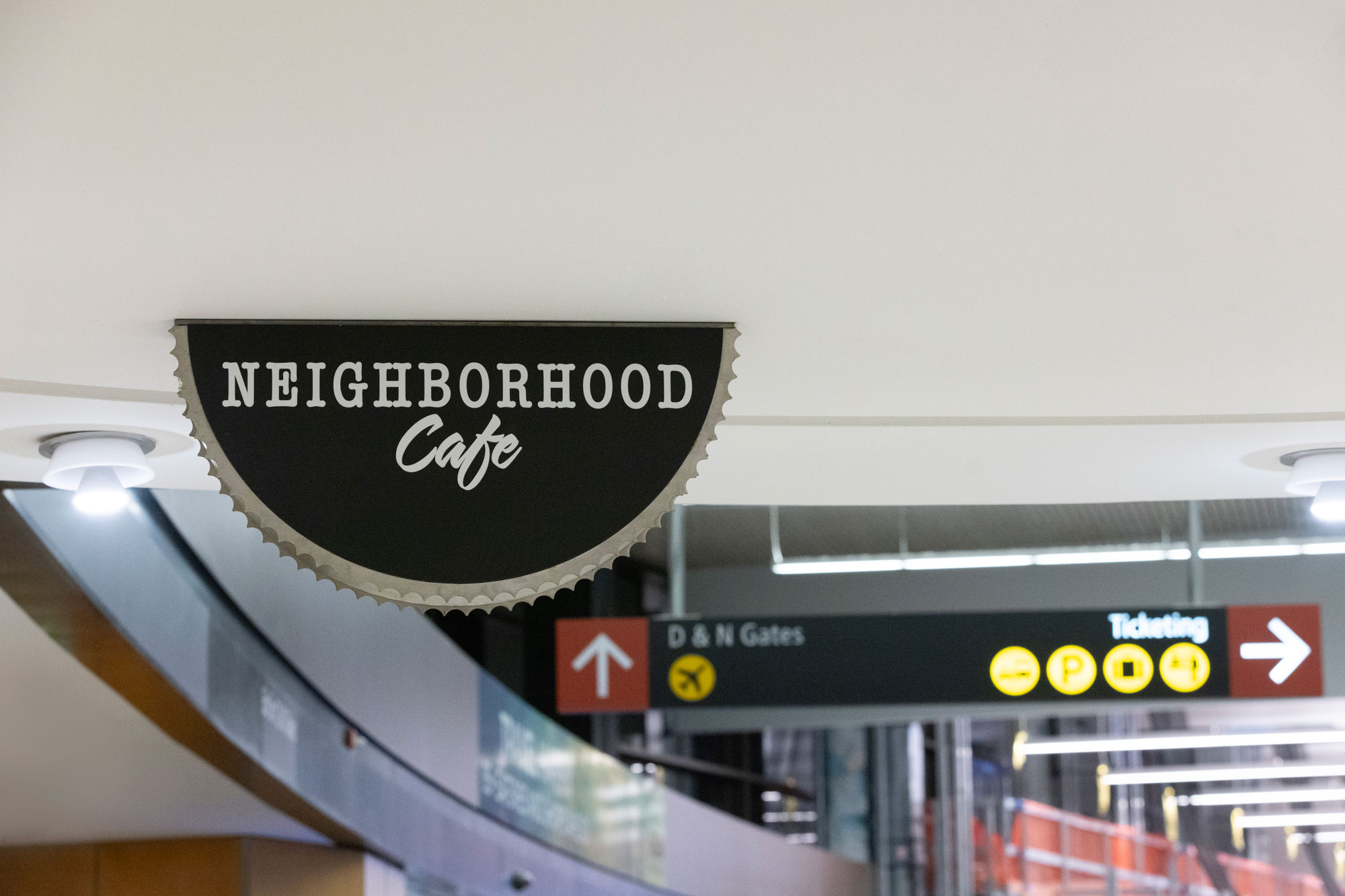 Neighborhood Cafe blade sign with airport signage in the background