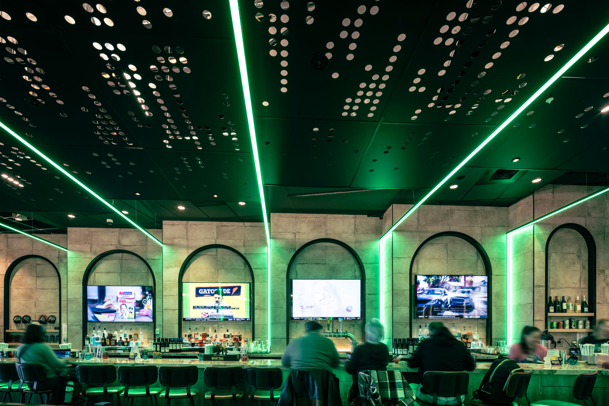 Sky Gamerz with travelers sitting at bar with green mood lighting